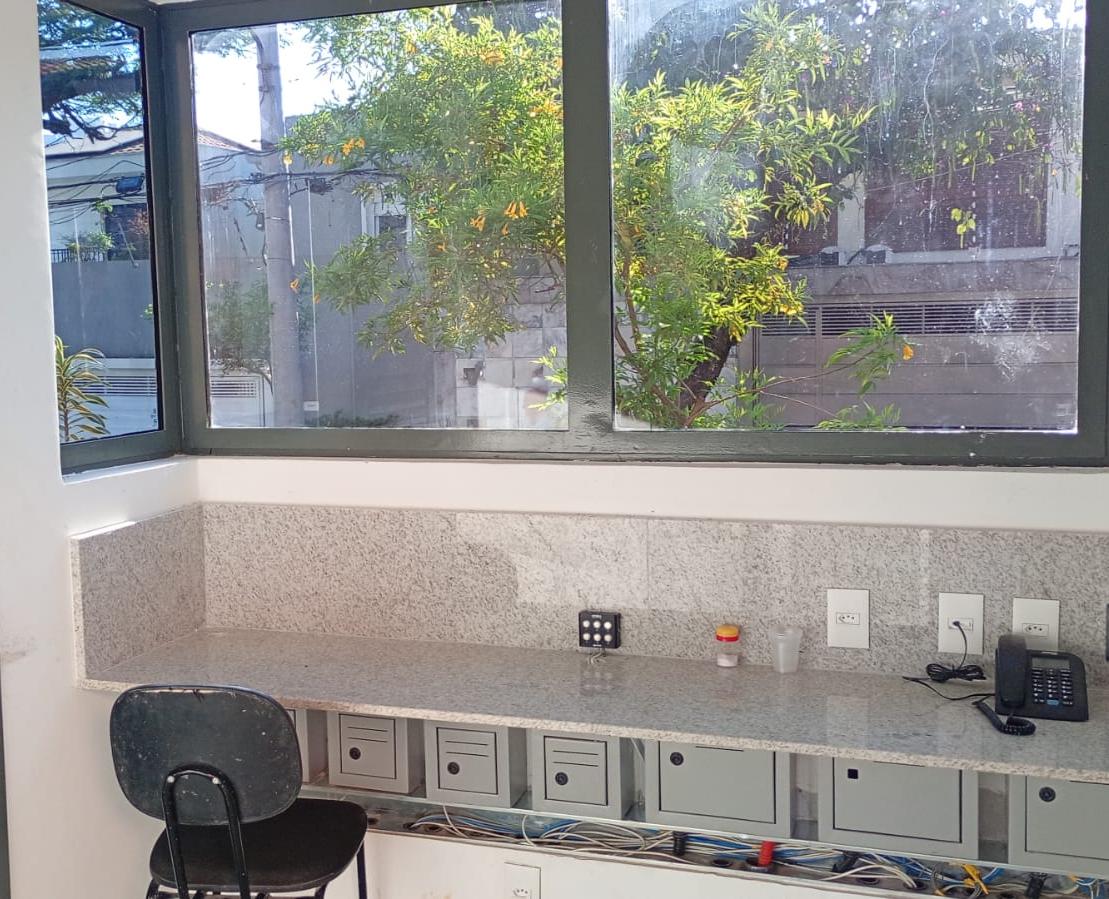Sala envidraçada com bancada em granito e vista para o jardim