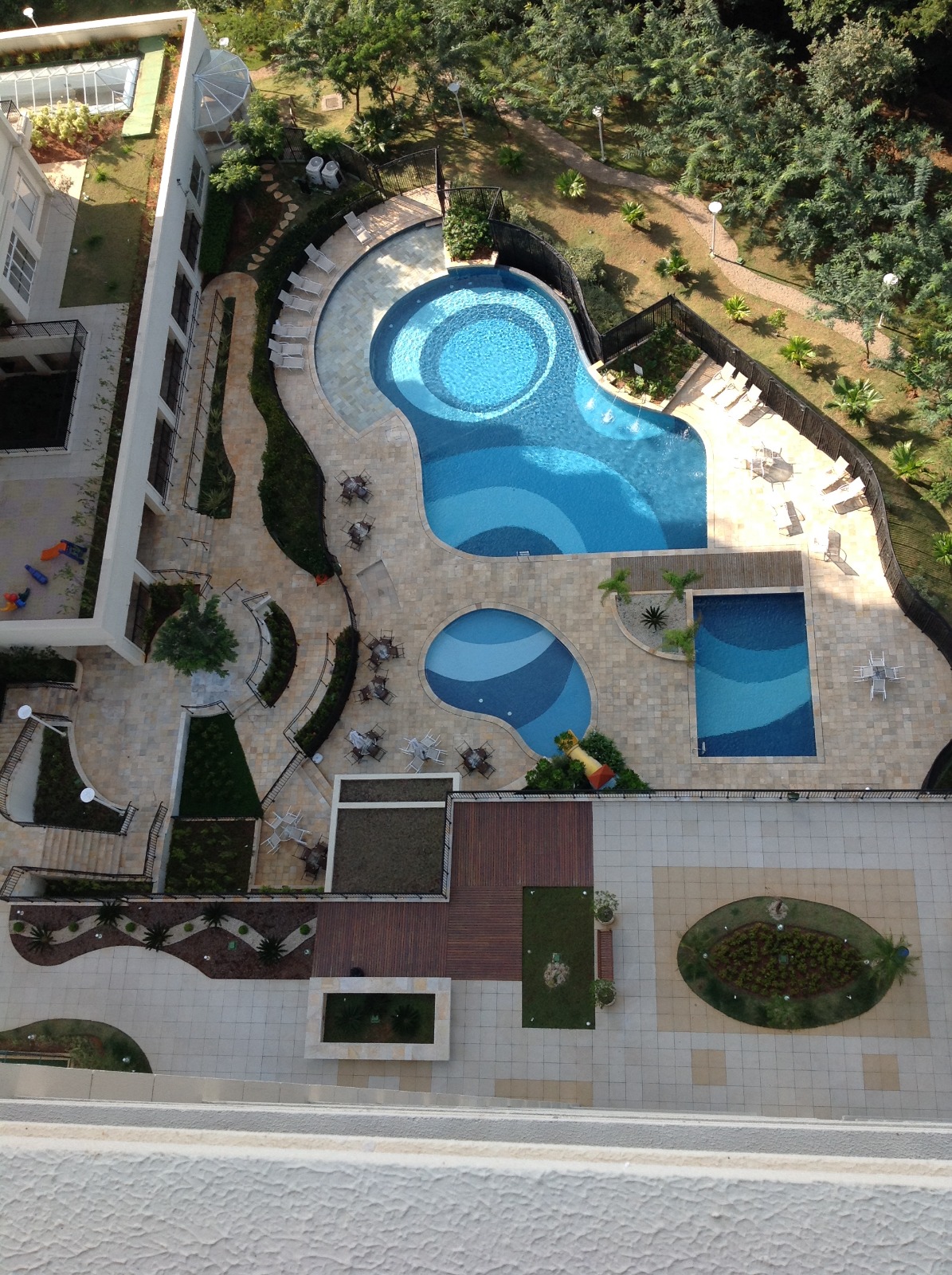 Vista aérea de piscinas, decks e jardins de condomínio residencial