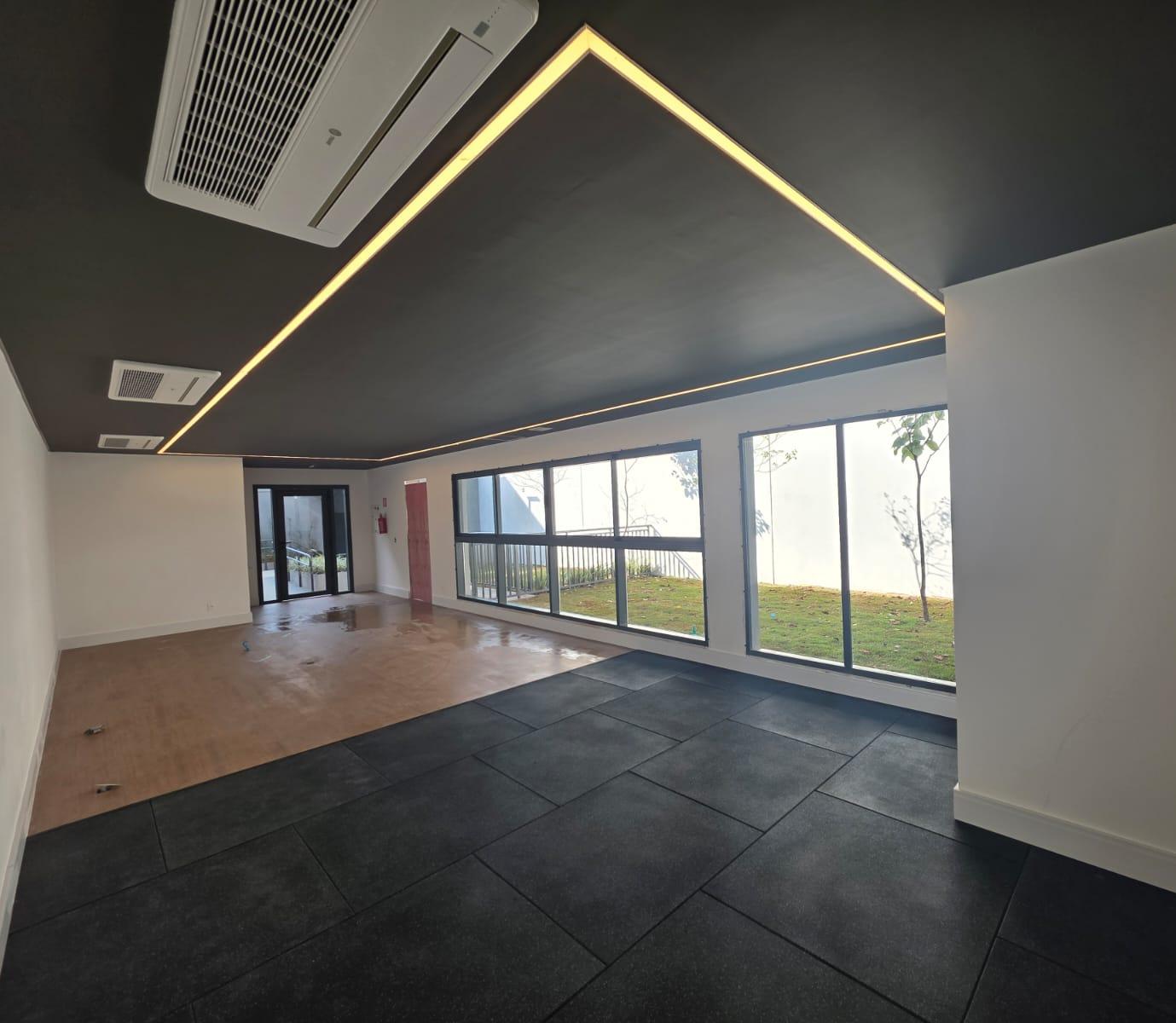 Salão com iluminação linear embutida no forro e piso escuro